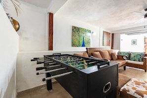 A room with a foosball table, a sofa, and a painting on the wall. - Bluebird Room - Brisal Mountain Retreat (Jarabacoa)