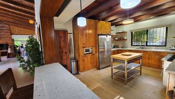 A modern kitchen with wooden cabinets, a stainless steel refrigerator, and a dining area with a table and chairs.