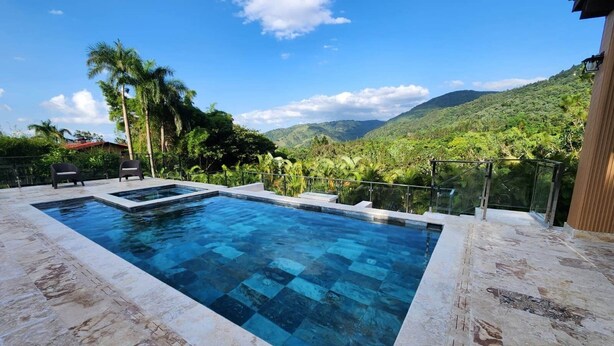 A rectangular swimming pool with clear blue water, surrounded by a stone deck. - Brisal Mountain Retreat (Jarabacoa)