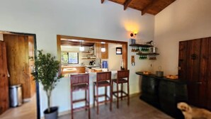 A wooden interior with a kitchen area, a dining table with chairs, and a potted plant. - Brisal Mountain Retreat (Jarabacoa)