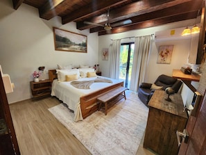A bedroom with a large bed, a wooden desk, a globe, and a painting on the wall.