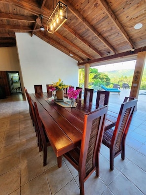 A wooden dining table with chairs, a vase with flowers, and a ceiling light fixture.