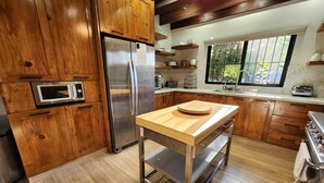 A modern kitchen with wooden cabinets, stainless steel appliances, and a wooden island. - Brisal Mountain Retreat (Jarabacoa)