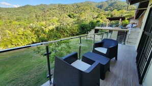 A balcony with wicker furniture overlooking a lush green landscape and mountains. - Brisal Mountain Retreat (Jarabacoa)