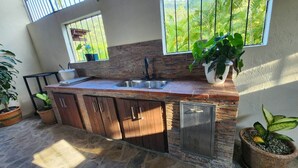A kitchen with a stone countertop, wooden cabinets, a sink, and a window overlooking greenery.