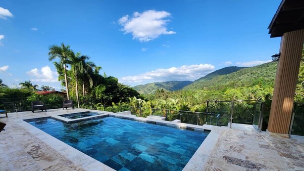 A rectangular swimming pool with a clear blue water, surrounded by a stone deck.