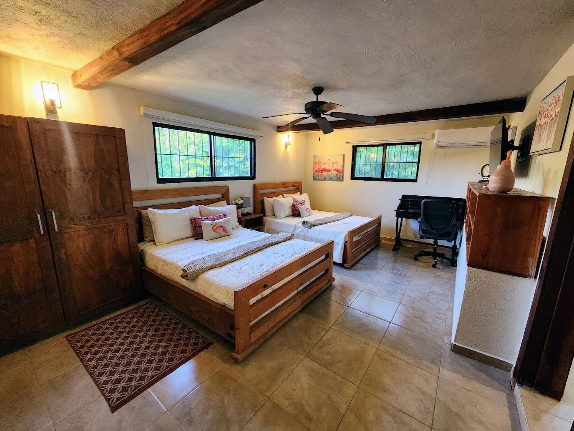 A bedroom with two beds, a desk, and a wardrobe.
