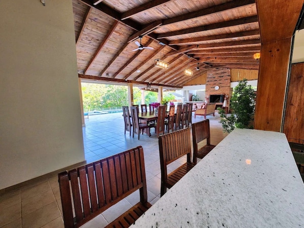 Un espacio de comedor al aire libre cubierto con bancos y mesas de madera, una pared de ladrillo y vistas a zonas verdes.