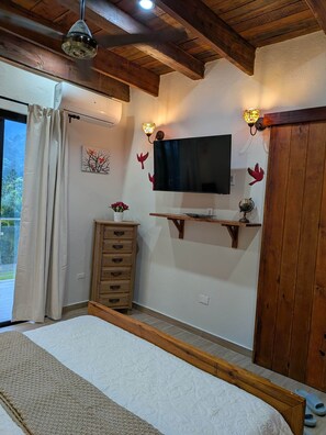 A bedroom with a bed, wooden dresser, TV, and decorative wall sconces.