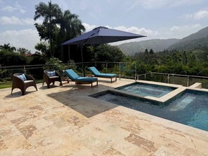 A pool area with lounge chairs and a large umbrella.