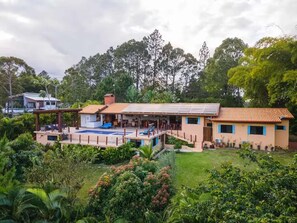 Una casa moderna con piscina, paneles solares y abundante vegetación.