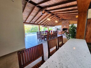 Un espacio de comedor al aire libre cubierto con bancos y mesas de madera, una pared de ladrillo y vistas a zonas verdes.