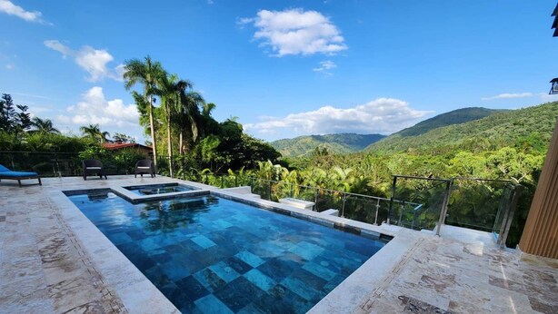 A rectangular infinity pool with a clear view of the surrounding landscape, including hills and palm trees.