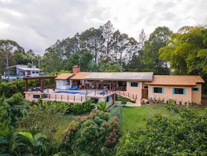 A modern house with a swimming pool, solar panels, and lush greenery.
