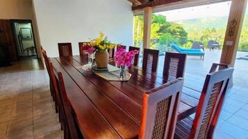 A wooden dining table with chairs, a vase with flowers, and a ceiling light fixture.