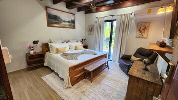 A bedroom with a large bed, a wooden desk, a globe, and a painting on the wall.