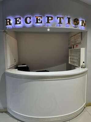 Balcão de atendimento com uma placa que diz 'RECEPTION' em letras iluminadas.