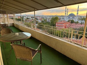 Varanda com móveis de vime e vista para a paisagem urbana, incluindo uma mesquita com minaretes.