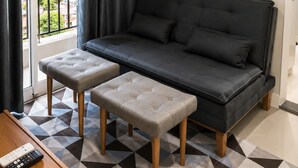Een moderne woonkamer met een bank, twee voetenbankjes, een salontafel en een afstandsbediening.