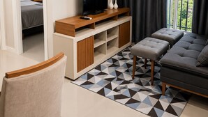 Een moderne woonkamer met een televisie, bank, poefs en een vloerkleed met een geometrisch patroon.
