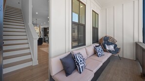 Een modern interieur met een trap, een bank met opvallende kussens en grote ramen.