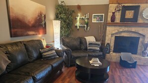 Ein Wohnzimmer mit einer Ledersofa, einem runden Couchtisch, einem Kamin und einem Stadtbildgemälde.