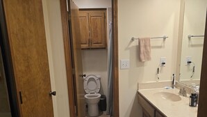 Ein Badezimmer mit Toilette, Waschbecken, Spiegel und Holzausstattung.