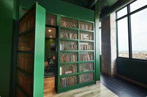 A room with a large green bookshelf, a view through a window, and a wooden floor. - Cozy Murphy Hideaway Studio 18th (Birmingham)