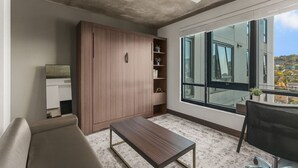 A modern living room with a large wardrobe, a sofa, a coffee table, and a dining area with a chair. - Cozy Murphy Hideaway Studio 18th (Birmingham)