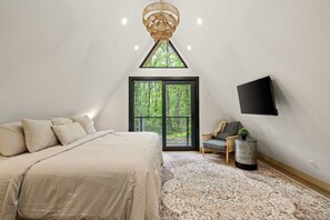 Una camera da letto con un letto, un'ampia finestra, una televisione e un comodino.