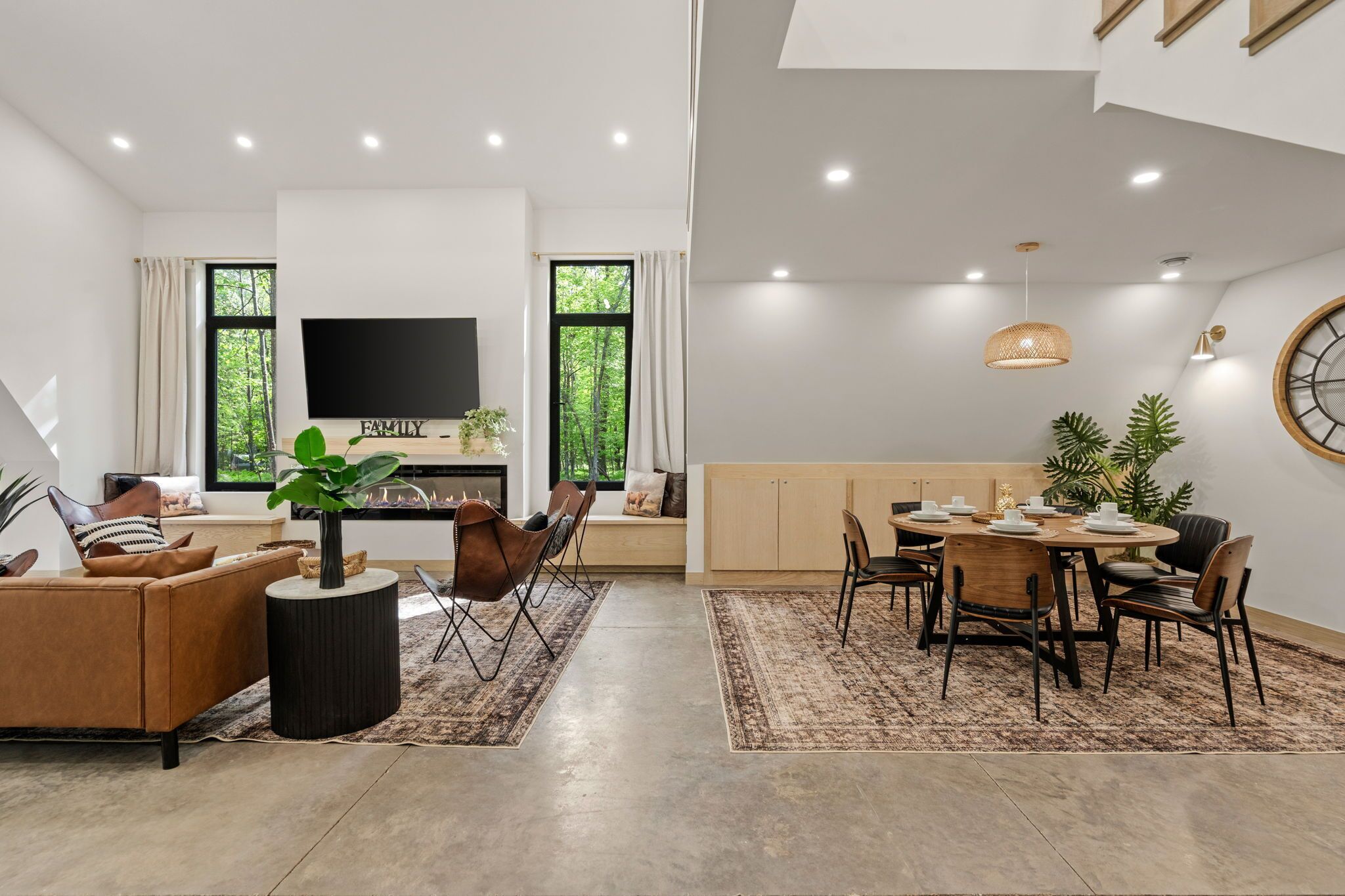 A modern living room with a sofa, TV, and dining area with chairs and a table.