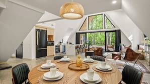 Un loft moderno con comedor que incluye una mesa redonda, sillas de cuero negro y un amplio ventanal con vistas al exterior.