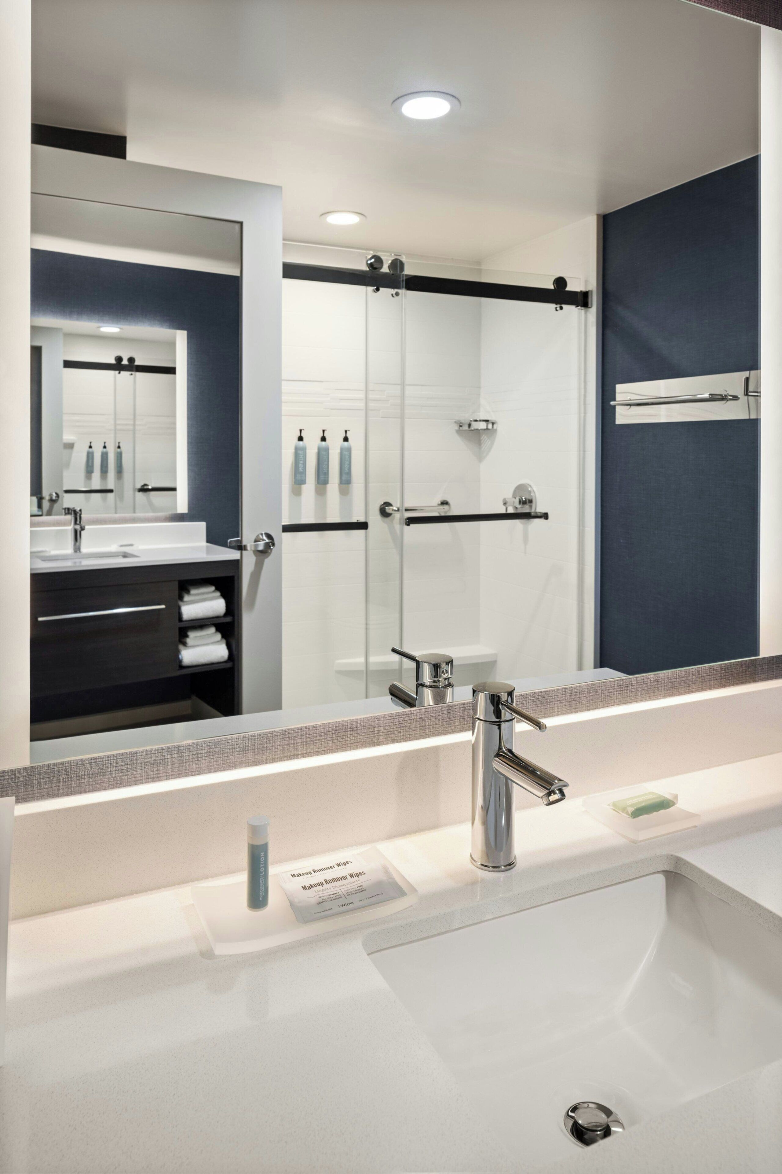 A modern bathroom with a large mirror, a sink, and a shower area.
