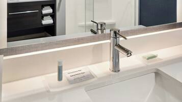 A modern bathroom with a large mirror, a sink, and a shower area.