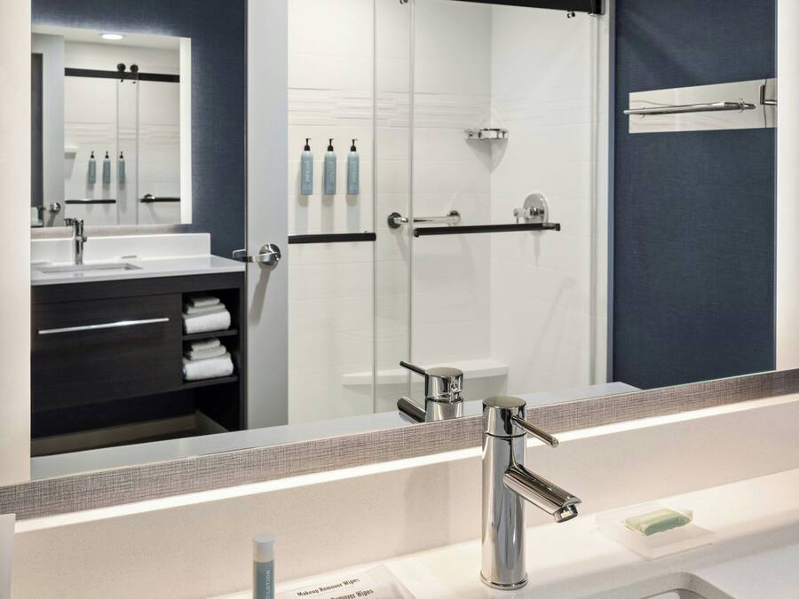 A modern bathroom with a large mirror, a sink, and a shower area.