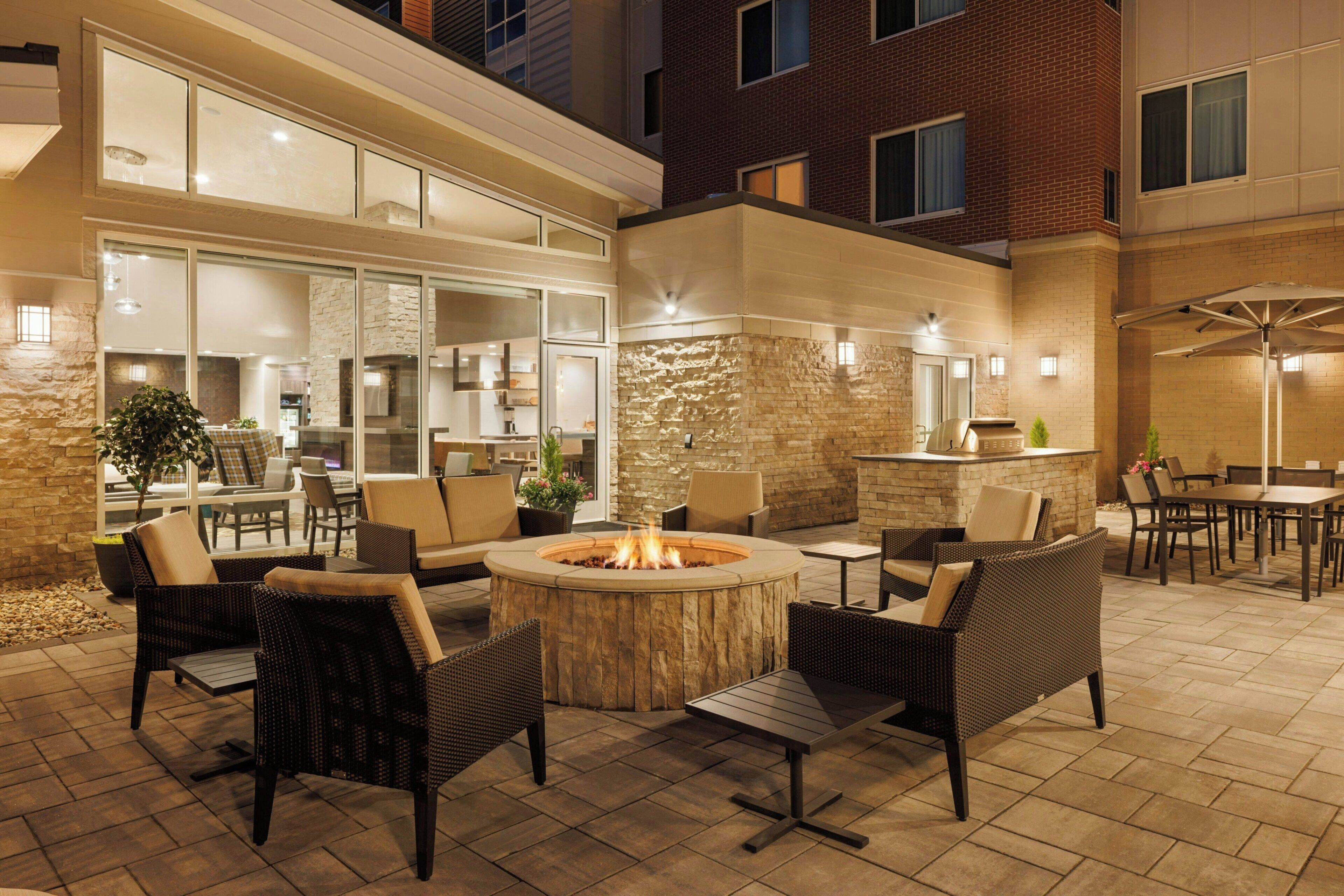 An outdoor patio area with a fire pit, seating, and a bar.