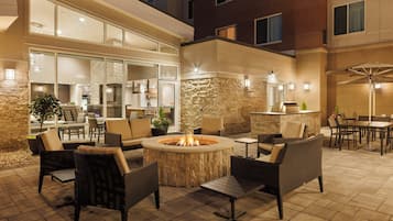 An outdoor patio area with a fire pit, seating, and a bar.