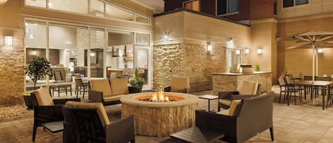 Un espacio al aire libre con patio, una chimenea, asientos y una barra.
