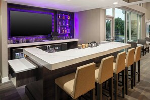 Ein stilvoller Barbereich mit einem großen Fernseher, Barhocker und einem Weinschränkchen.