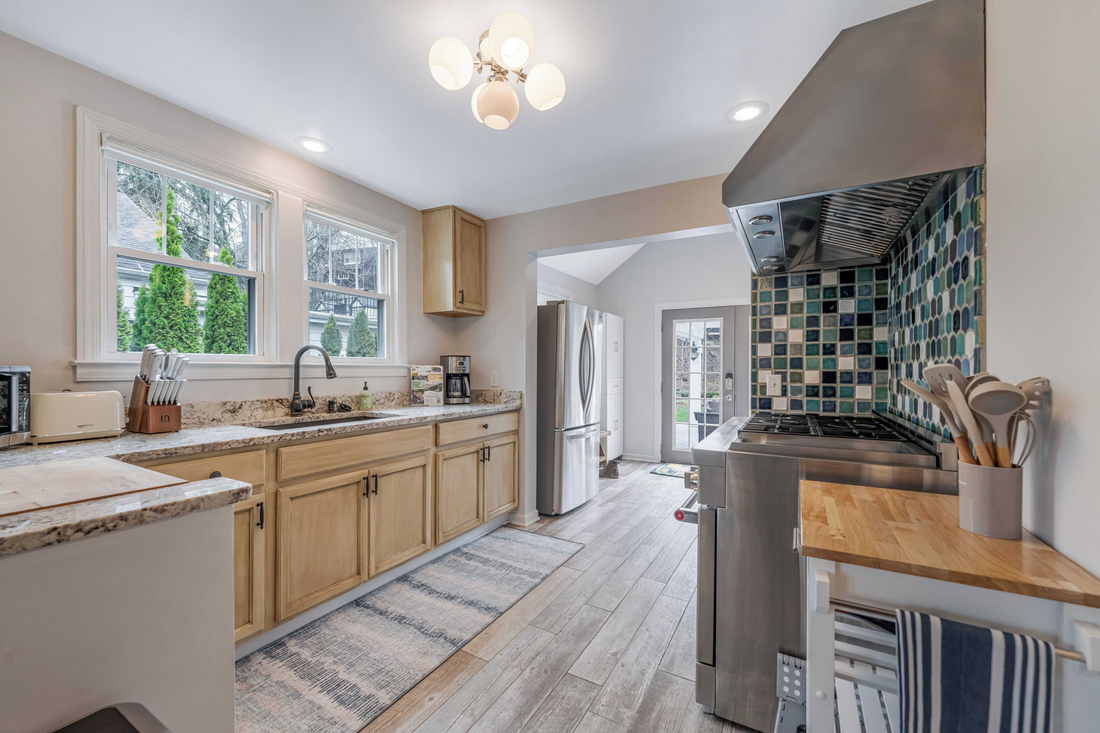 A modern kitchen with wooden cabinets, a stainless steel refrigerator, and a tiled backsplash.
