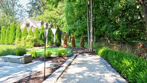 A pathway leading to a house surrounded by greenery and trees.