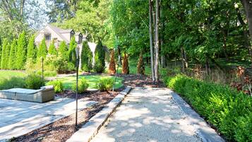 A pathway leading to a house surrounded by greenery and trees.