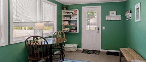 A room with a dining table, chairs, a bookshelf, a door, and a ceiling fan.