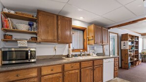 Una cocina con armarios de madera, microondas, lavavajillas y encimera de granito.