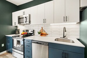 A modern kitchen with white cabinets, stainless steel appliances, and a dishwasher. - Fortissimo - Pool - Gym - Mins to Broadway (Nashville)