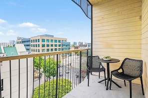 A balcony with a view of buildings, a round table, and two chairs. - Fortissimo - Pool - Gym - Mins to Broadway (Nashville)