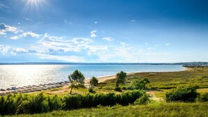 A coastal landscape with a beach, grassy areas, and a clear sky. - Pool Apartment Rose 1, Privlaka, Croatia (Privlaka)