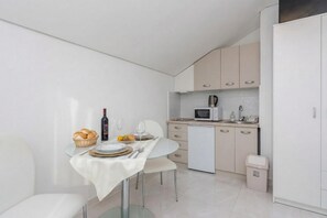 A modern kitchen with a dining area, white cabinetry, a microwave, and a small trash bin. - Pool Apartment Sea 2, Privlaka, Croatia (Privlaka)