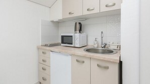 A compact kitchen with a microwave, a coffee maker, a sink, and a dishwasher. - Pool Apartment Sea 2, Privlaka, Croatia (Privlaka)
