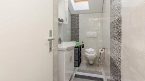 A compact bathroom with a skylight, a sink, a toilet, and a small storage unit. - Pool Apartment Sea 2, Privlaka, Croatia (Privlaka)